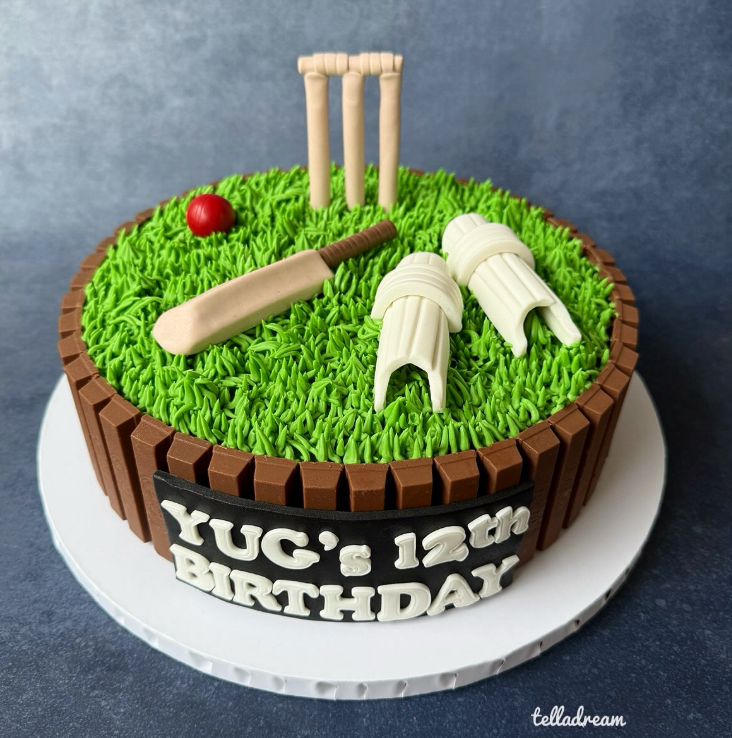 Cricket-themed birthday cake with grass icing, wickets, bat, ball and KitKat border